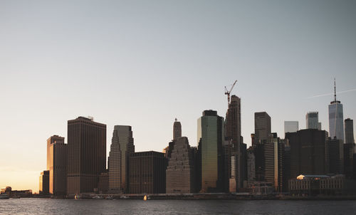 Modern buildings by sea against clear sky