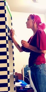 Side view of woman standing against wall at home