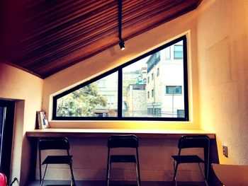 Empty chairs and table against window