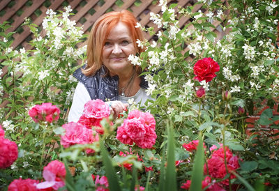 Portrait of senior woman with red flowering plants