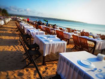 Chairs and tables at beach against sky