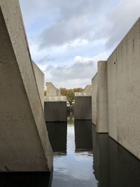 Bridge over river by buildings against sky