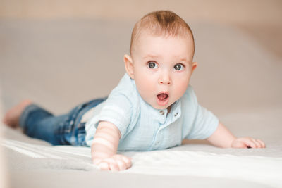 Portrait of cute baby boy sitting on bed at home