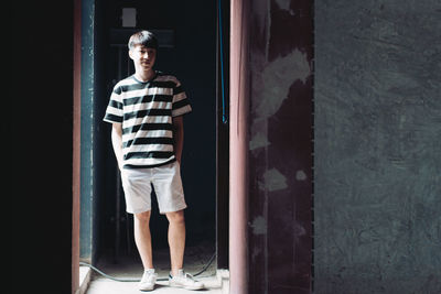 Portrait of young man standing by door