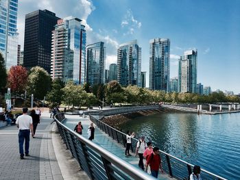 People on modern buildings in city against sky