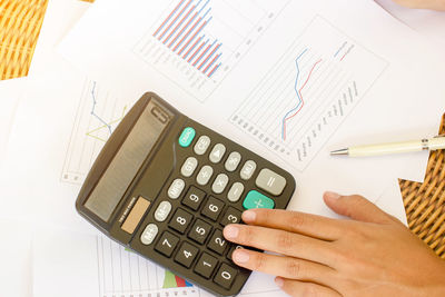 Cropped hand of business person using calculator in office