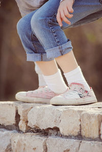 Low section of girl wearing shoes