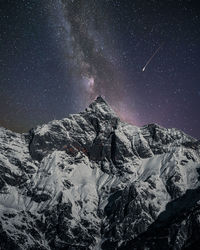 Scenic view of snowcapped mountains against sky at night