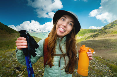Young cheerful beautiful female hiker walking in the mountains in summer - active female lifestyle