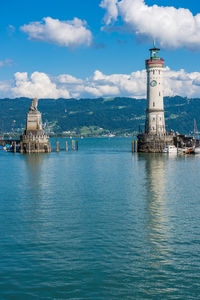 Lighthouse on building by sea against sky