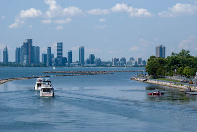 Nautical vessel on sea by buildings in city against sky