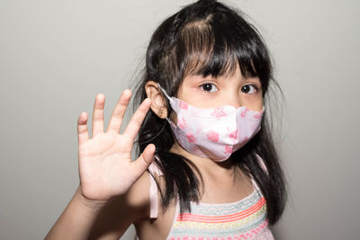 Close-up portrait of girl wearing mask against gray background