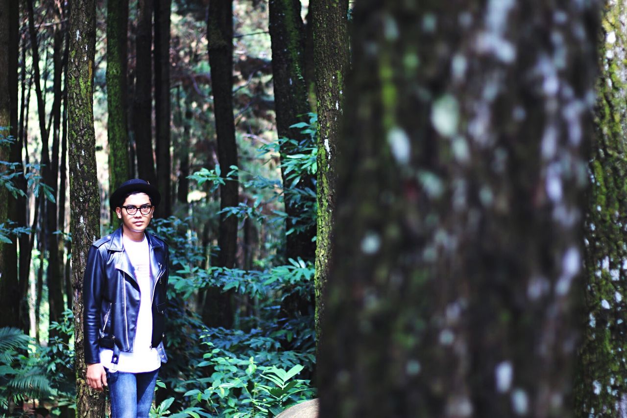 tree, tree trunk, forest, lifestyles, leisure activity, casual clothing, portrait, nature, growth, woodland, day, outdoors, tranquility, plant, focus on foreground, beauty in nature, green color