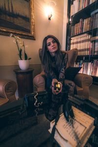 Woman holding book while sitting at home