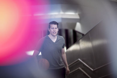 High angle portrait of young man with basketball moving up on steps