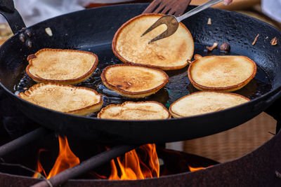 Cooking blini, blin or blynai, pancakes traditional sweet food, preparing outdoor on an open fire