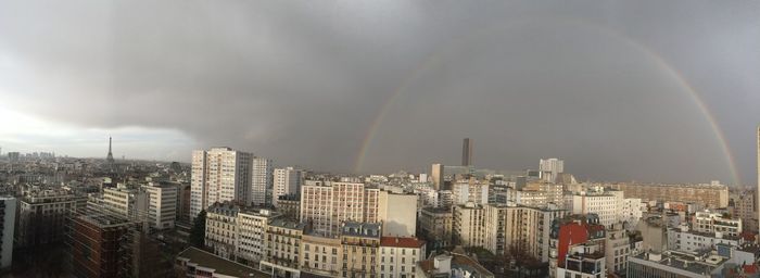 Aerial view of rainbow over buildings in city against sky