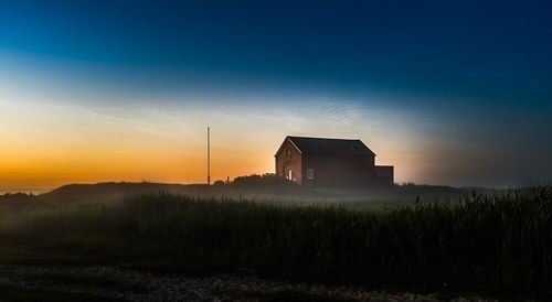 Silhouette house on field against sky during sunset