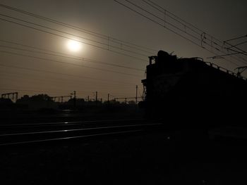 Silhouette railroad tracks against sky during sunset