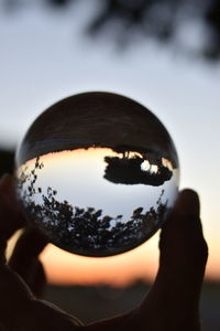 Close-up of person holding glass against sky
