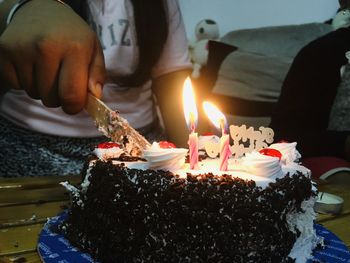 Midsection of man holding lit candle