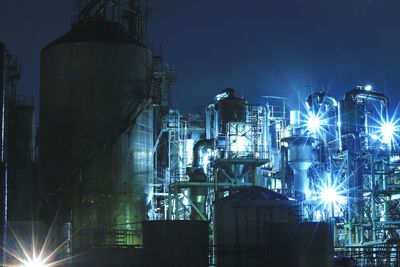 Illuminated factory against sky at night