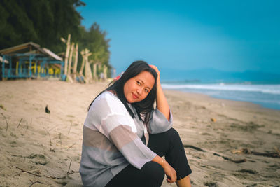 Young woman standing on beach against sky