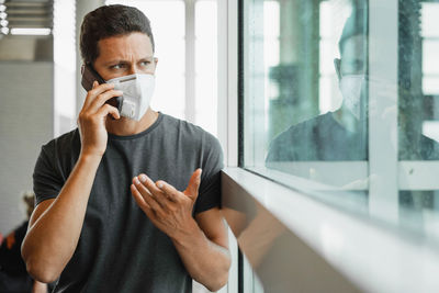 Portrait of young man drinking glass window