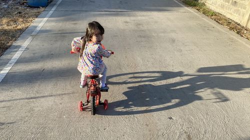 Rear view of girl bicycling on road