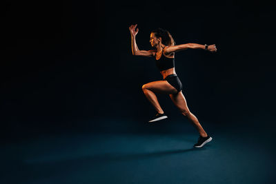 Full length of woman running against black background