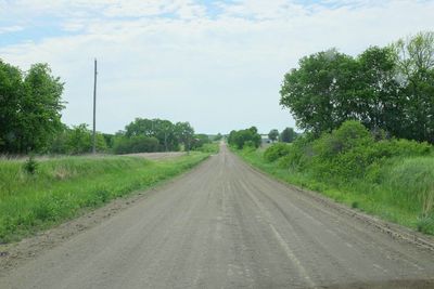 Road amidst field against sky