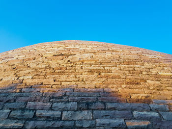 Low angle view of stone wall against blue sky