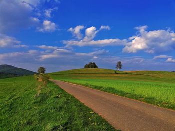 Road amidst field against sky