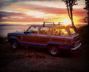 Car on beach against sky during sunset