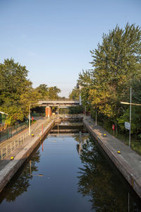 Swimming pool by trees against clear sky