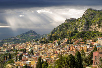 Aerial view of townscape by tree mountain against sky