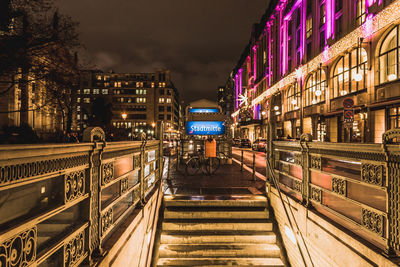 Illuminated bridge amidst buildings in city at night