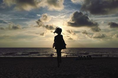 Silhouette of woman jumping on beach