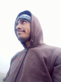 Portrait of young man looking away against sky