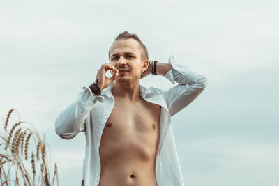 Low angle view of shirtless man standing against sky