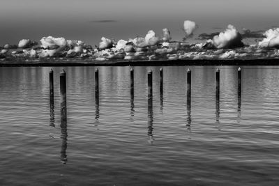 Wooden posts in sea against sky