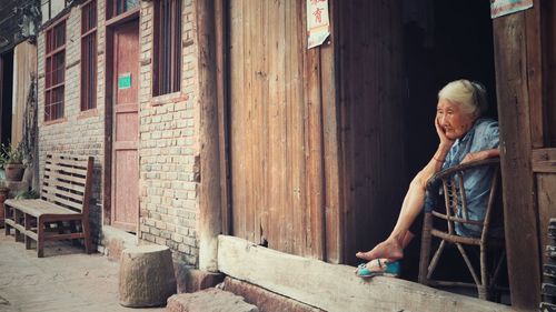 Full length of woman sitting outside house