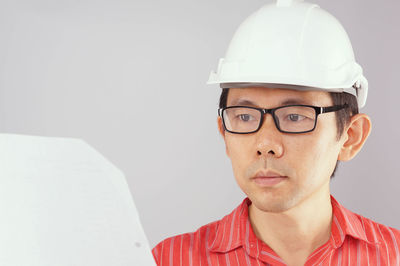 Man wearing eyeglasses holding paper against white background