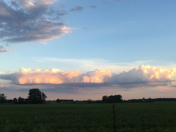 Scenic view of grassy field against cloudy sky