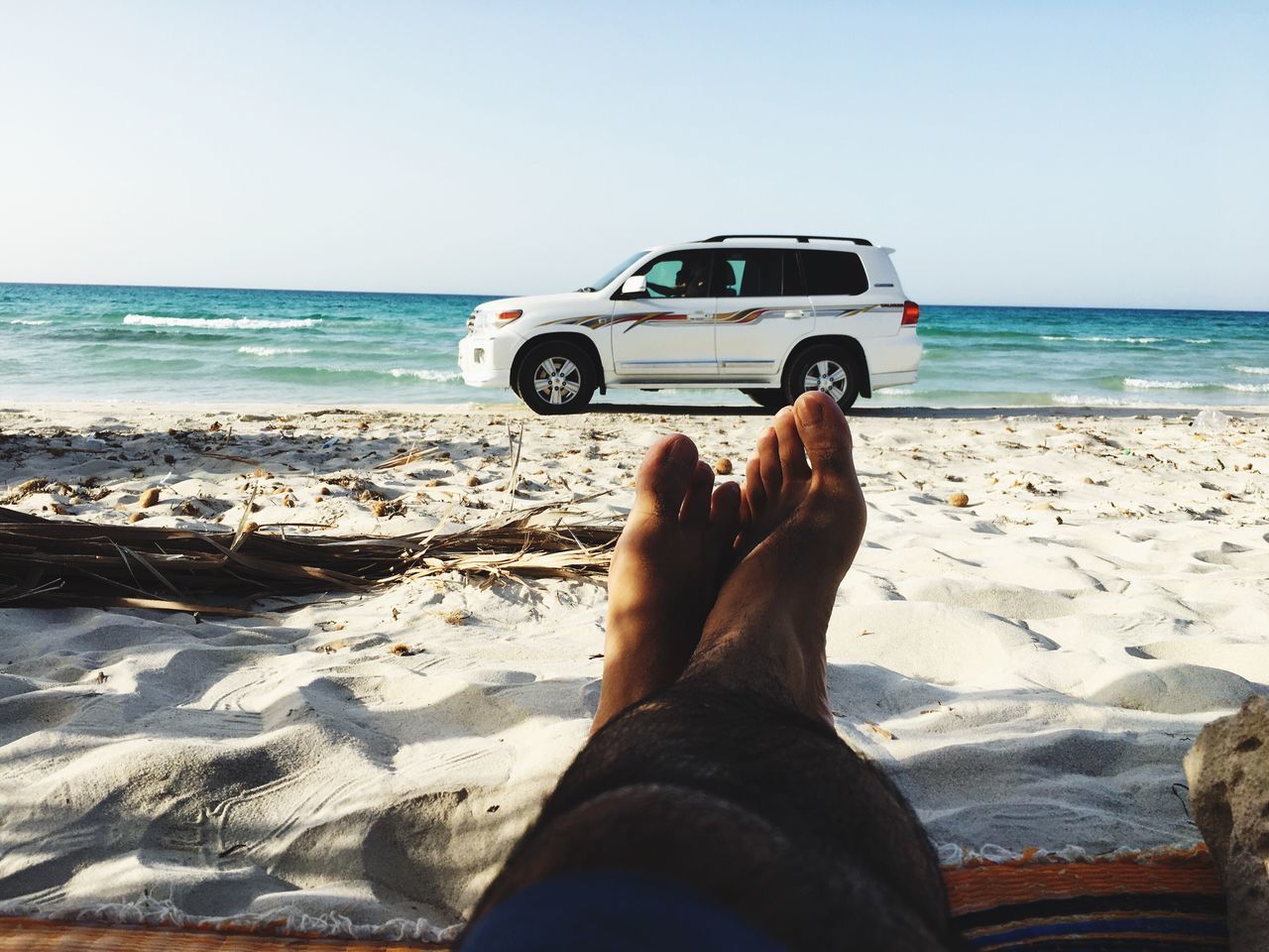 sea, beach, horizon over water, sand, low section, water, shore, real people, barefoot, personal perspective, nature, one person, leisure activity, vacations, scenics, beauty in nature, sunlight, day, clear sky, human leg, relaxation, outdoors, sky, lifestyles, wave, people