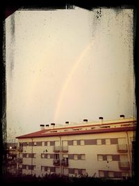 Rainbow over building against sky