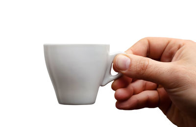 Close-up of hand holding cup over white background