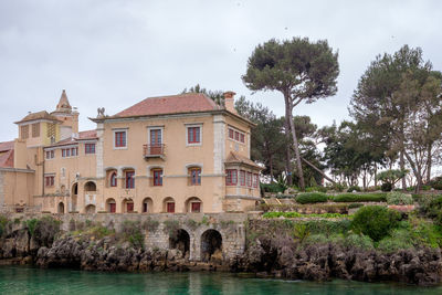 Buildings by river against sky