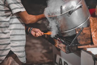 Midsection of man working on barbecue grill