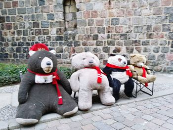 Stuffed toy on footpath against brick wall